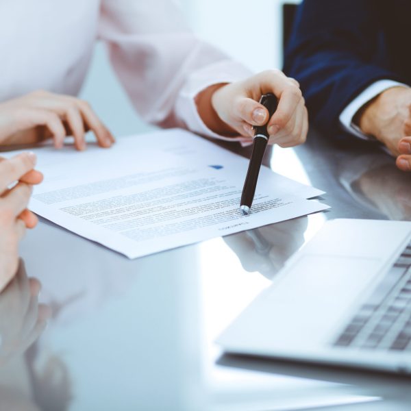 Gruppe von Geschäftsleuten und Anwälten, die an einem Tisch sitzen und Vertragsunterlagen besprechen, Nahaufnahme